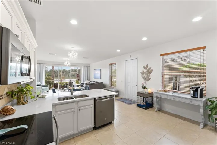 Kitchen featuring stainless steel appliances, light tile patterned flooring, sink, a notable chandelier, and white cabinets