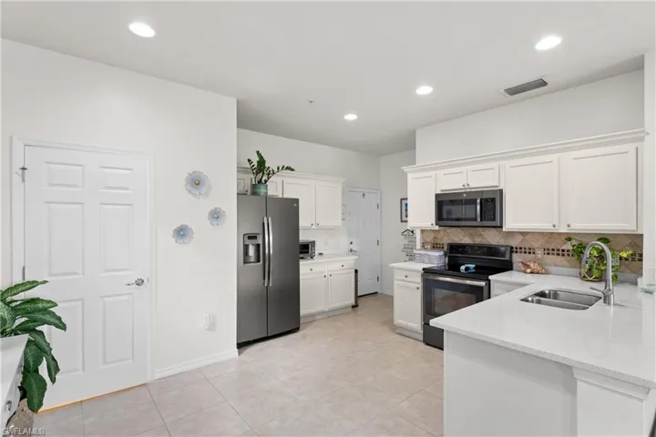 Kitchen with white cabinetry, sink, decorative backsplash, and appliances with stainless steel finishes