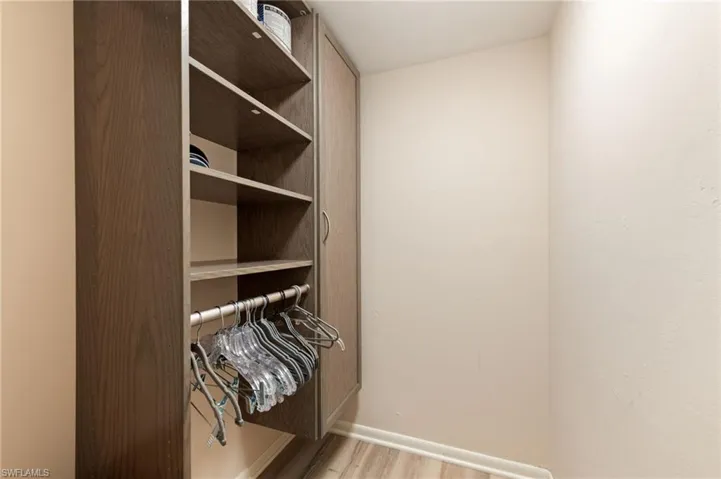 Custom Storage system featuring custom wood-finish shelving, vertical built-in cabinetry, and integrated hanging rod, complemented by CoreTec luxury vinyl plank flooring