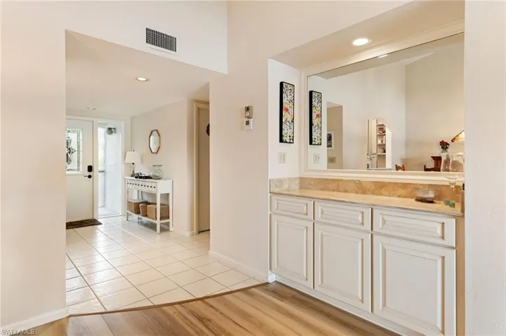 Built-in cabinetry featuring a stone-surface countertop, large wall-mounted mirror, recessed lighting, and combination tile and CoreTec luxury vinyl plank flooring