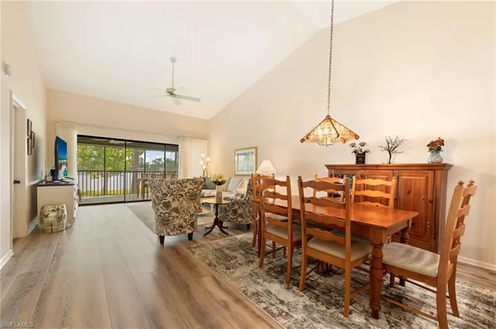 Open-concept living and dining area featuring vaulted ceilings, CoreTec luxury vinyl plank flooring, a ceiling fan, and large sliding glass doors