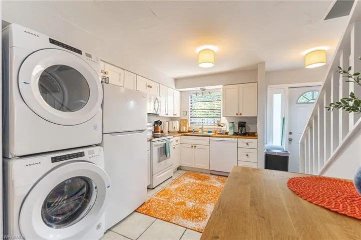 Washroom featuring light tile patterned floors and estacked washer and dryer