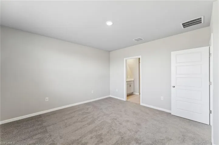 Unfurnished bedroom featuring light colored carpet and ensuite bathroom