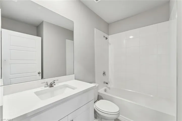 Full bathroom with tiled shower / bath, vanity, and toilet