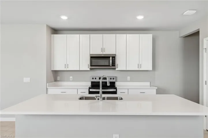 Kitchen featuring appliances with stainless steel finishes, sink, a center island with sink, and white cabinets