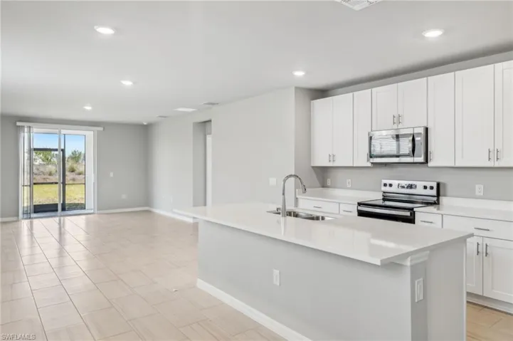 Kitchen featuring white cabinetry, stainless steel appliances, sink, and a kitchen island with sink