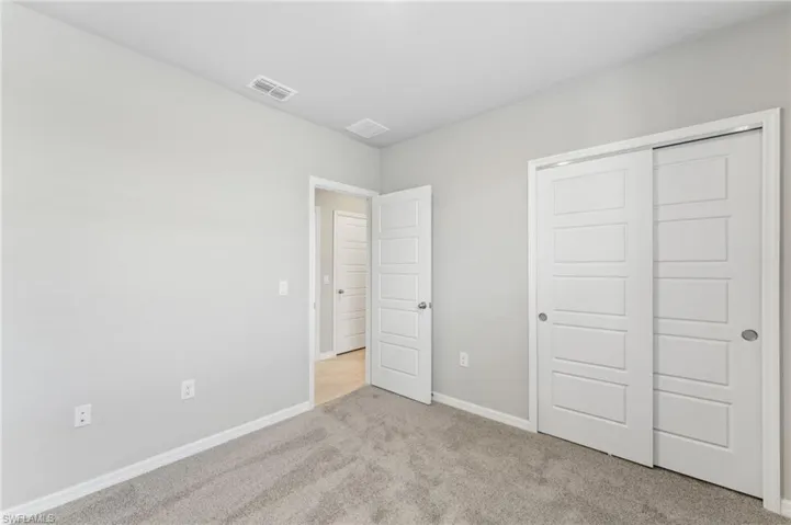 Unfurnished bedroom featuring light carpet and a closet