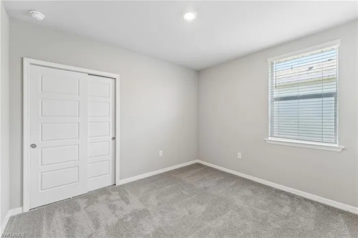 Unfurnished bedroom with light carpet and a closet