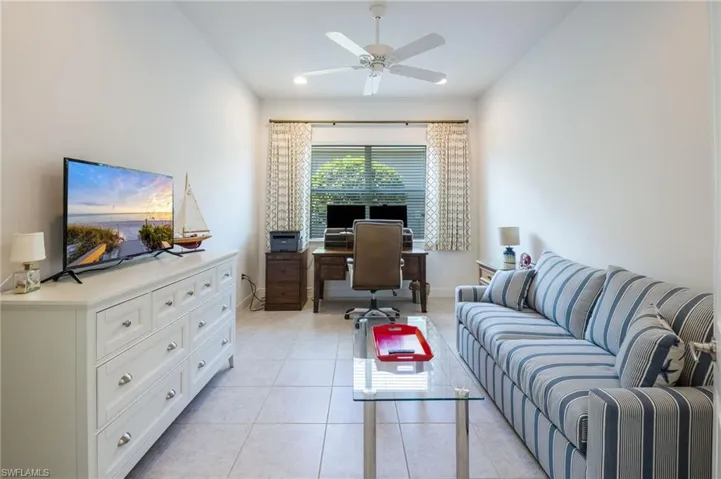 Open-concept living space featuring neutral tile flooring, recessed lighting, and a tray ceiling with a modern ceiling fan