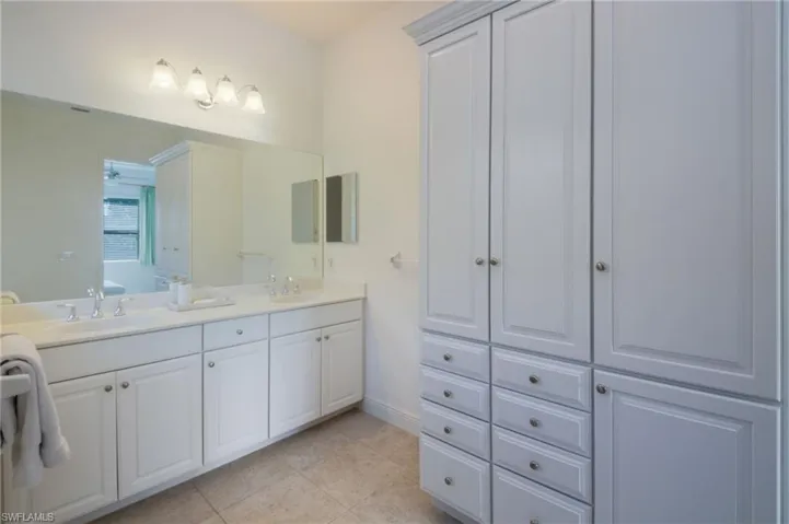 Bathroom featuring a white vanity with an integrated sink, polished chrome faucet, and a large wall-mounted mirror