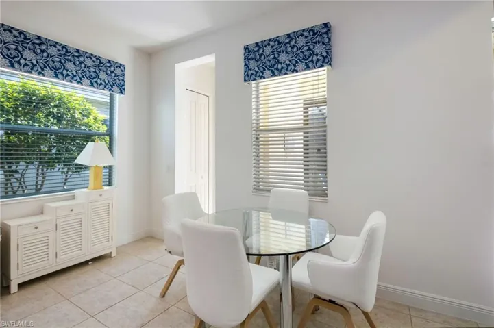 Dining area featuring neutral tile flooring, a tray ceiling, and an accent wall