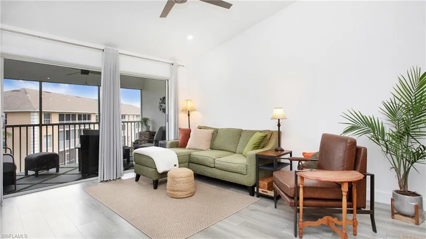 Living area with ceiling fan, vaulted ceiling, and light wood-type flooring