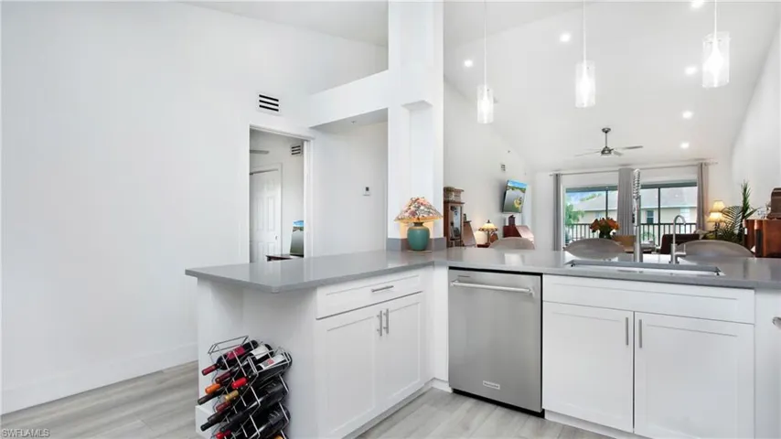 Kitchen with stainless steel dishwasher, light wood finished floors, white cabinets, a sink, and a ceiling fan