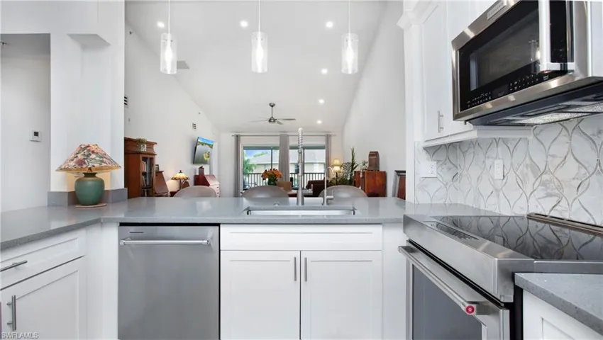Kitchen featuring stainless steel appliances, backsplash, a ceiling fan, white cabinetry, and recessed lighting