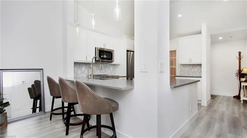 Kitchen featuring stainless steel appliances, a kitchen bar, light wood-type flooring, white cabinets, and recessed lighting