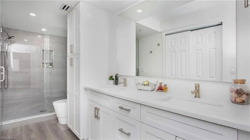 Bathroom with double vanity, a shower stall, toilet, recessed lighting, and wood finished floors