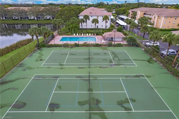 View of tennis court featuring a water view and a community pool