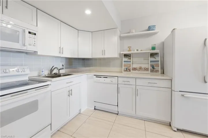 Kitchen featuring white appliances, open shelves, white cabinetry, and light countertops