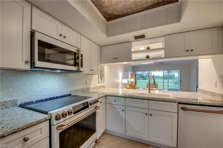 Kitchen with white cabinetry, white appliances, and decorative backsplash