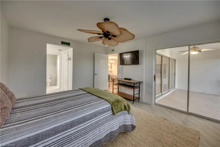 Bedroom featuring ceiling fan, a closet, light hardwood / wood-look tile flooring, and ensuite bath