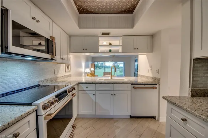 Kitchen with white cabinetry, white appliances, and decorative backsplash