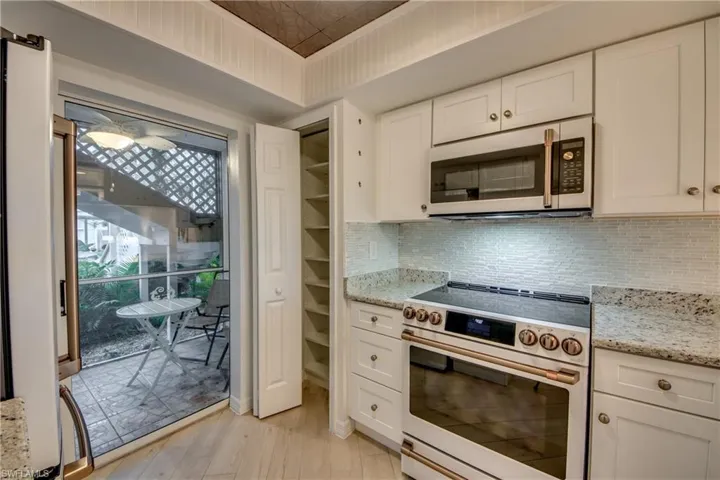Kitchen with white cabinetry, white appliances, and decorative backsplash