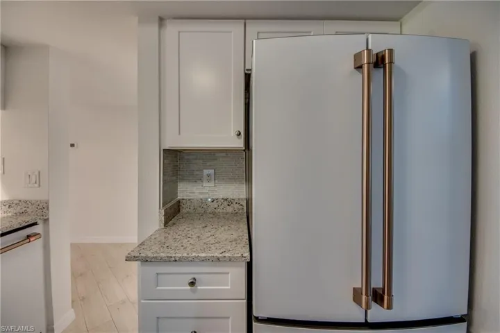 Kitchen with white cabinetry, white appliances, and decorative backsplash