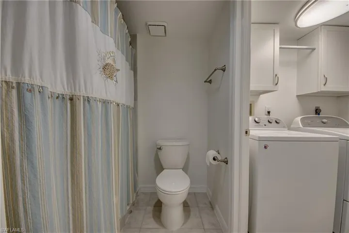 Bathroom with tile  flooring, vanity, and toilet and laundry room
