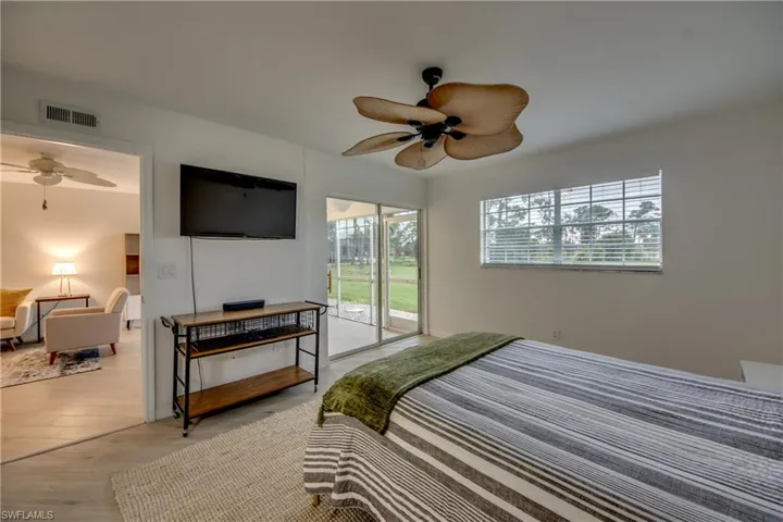 Bedroom featuring ceiling fan, wood-look tile floors, multiple windows, and sliding door to lanai