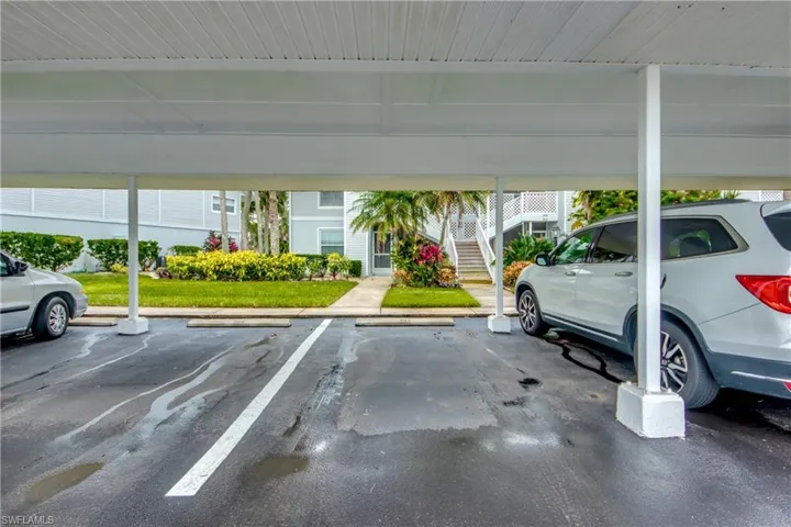 View of vehicle parking featuring a lawn and a carport
