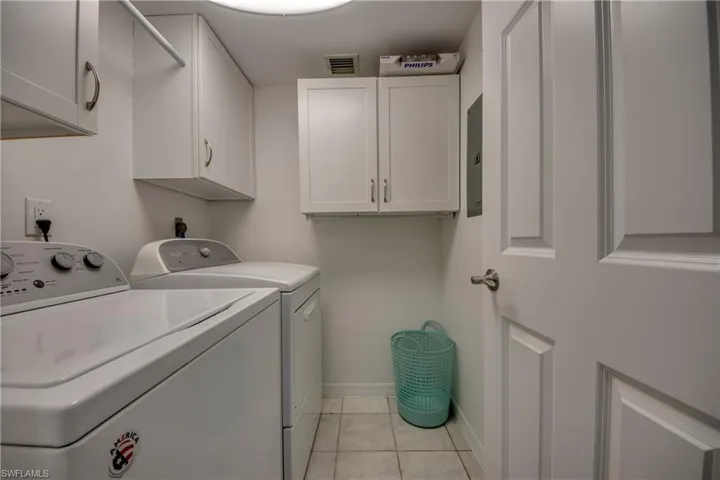 Laundry area featuring cabinets,  featuring a wealth of natural light washing machine and dryer, and light tile  flooring