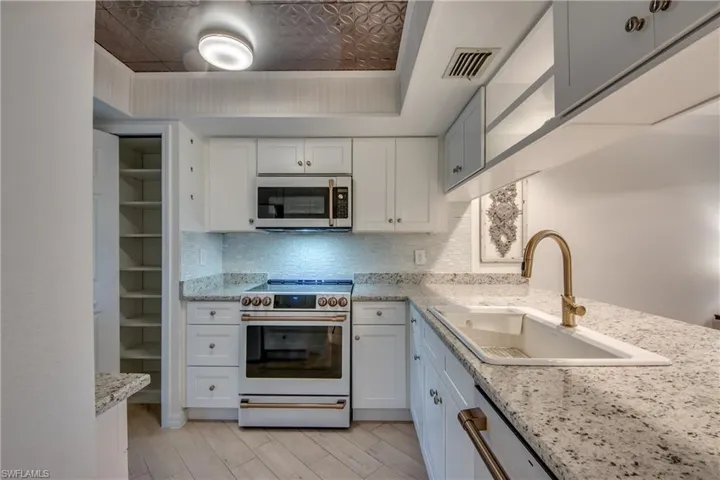 Kitchen with white cabinetry, white appliances, and decorative backsplash