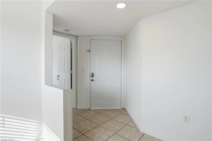 Hallway with baseboards and light tile patterned floors