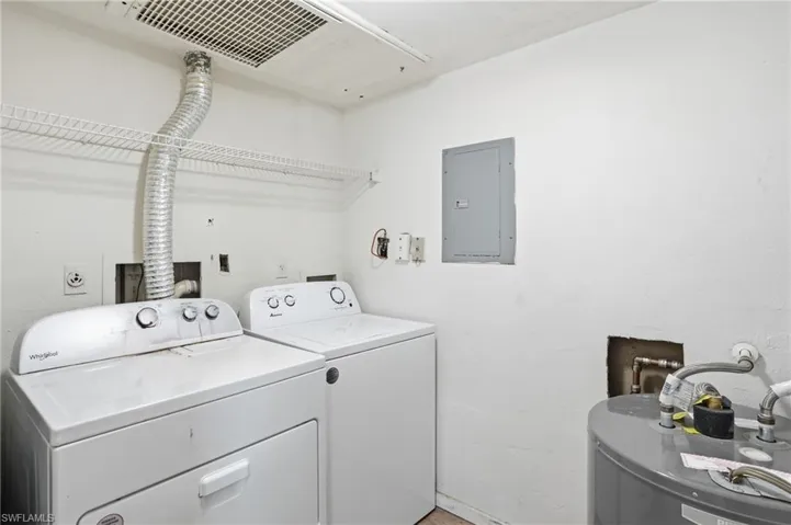 Laundry area with electric panel, water heater, and washing machine and clothes dryer