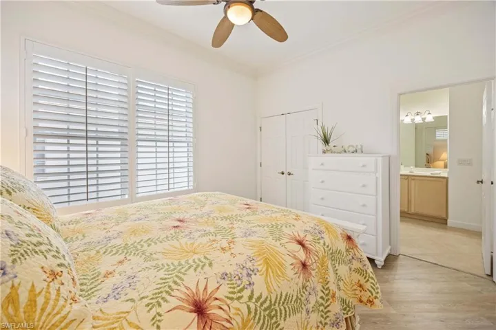 Bedroom with crown molding, a closet, light wood-type flooring, ceiling fan, and ensuite bath