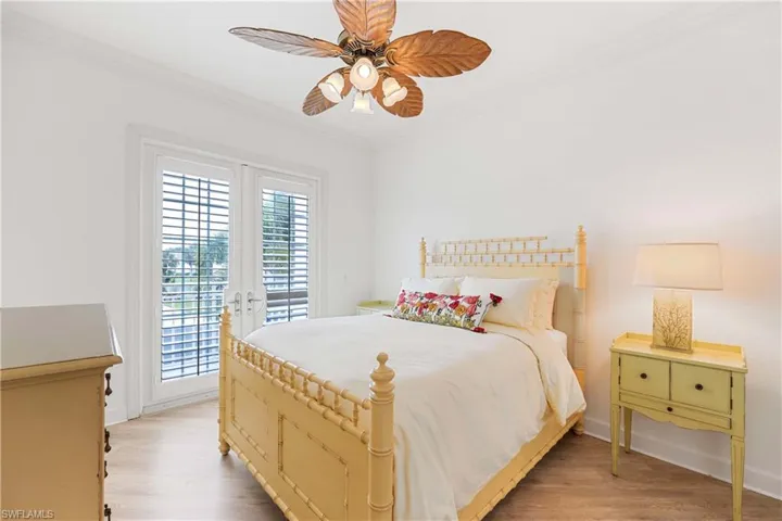Bedroom featuring access to exterior, crown molding, light wood-type flooring, and a ceiling fan