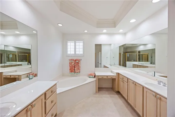 Bathroom featuring crown molding, a bath, a raised ceiling, a shower stall, and recessed lighting