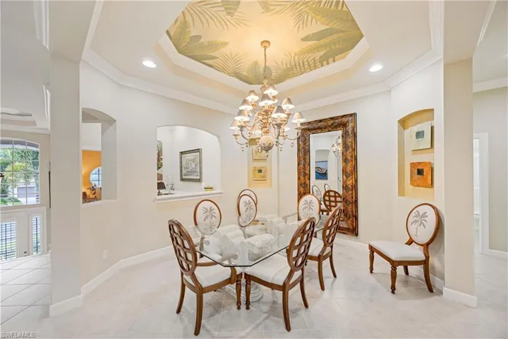Dining space featuring a raised ceiling, a chandelier, ornamental molding, light tile patterned floors, and recessed lighting
