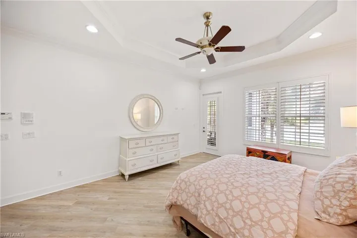 Bedroom featuring ornamental molding, a raised ceiling, access to exterior, light wood-style flooring, and recessed lighting