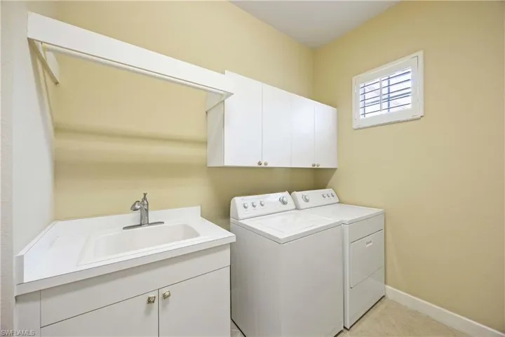 Laundry area featuring washing machine and clothes dryer, cabinet space, and light tile patterned floors