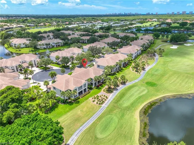 Aerial view of residential area featuring a nearby body of water, a local golf course, and city skyline