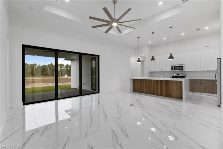 Kitchen featuring a large island with sink, white cabinets, a raised ceiling, and appliances with stainless steel finishes