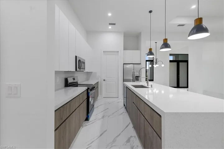 Kitchen featuring decorative light fixtures, white cabinetry, stainless steel appliances, tasteful backsplash, and a large island