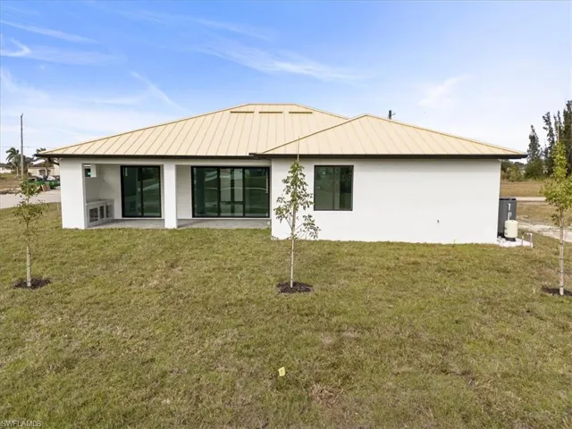 Back of property featuring a lawn and a patio