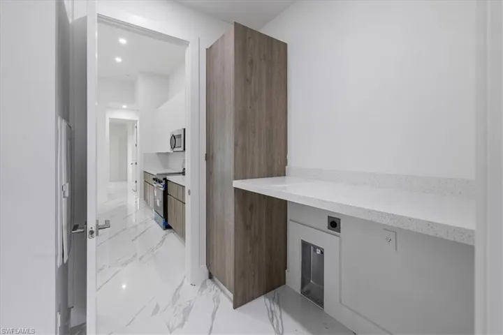 Kitchen featuring white cabinets, stainless steel appliances, and built in desk