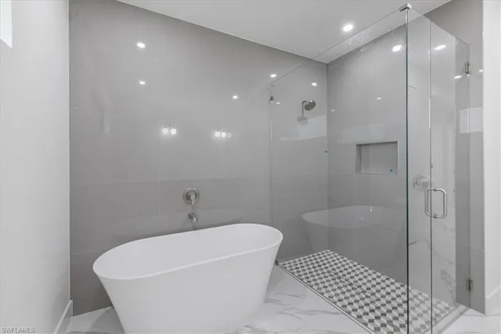 Bathroom featuring tile walls and independent shower and bath