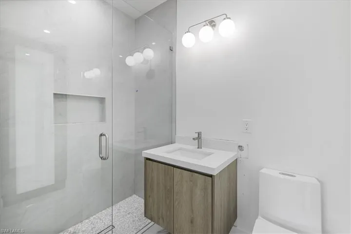 Bathroom with toilet, walk in shower, and vanity