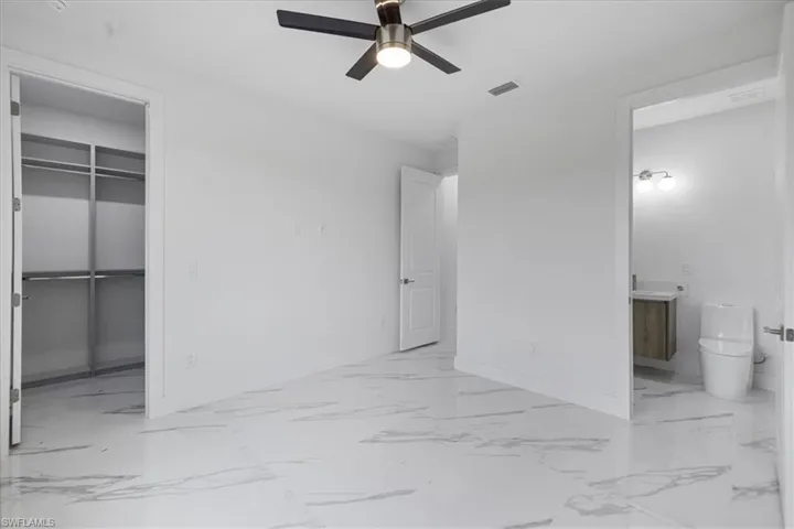Unfurnished bedroom with ceiling fan, a walk in closet, a closet, and connected bathroom