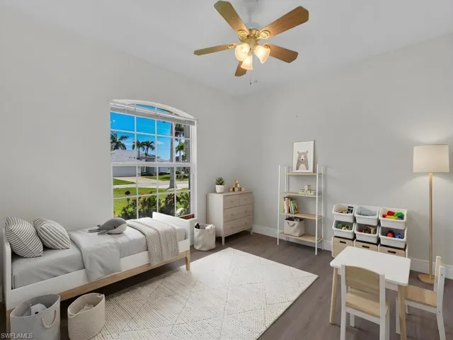 Spacious room featuring vaulted ceilings, wood-finish flooring, and a large arched window