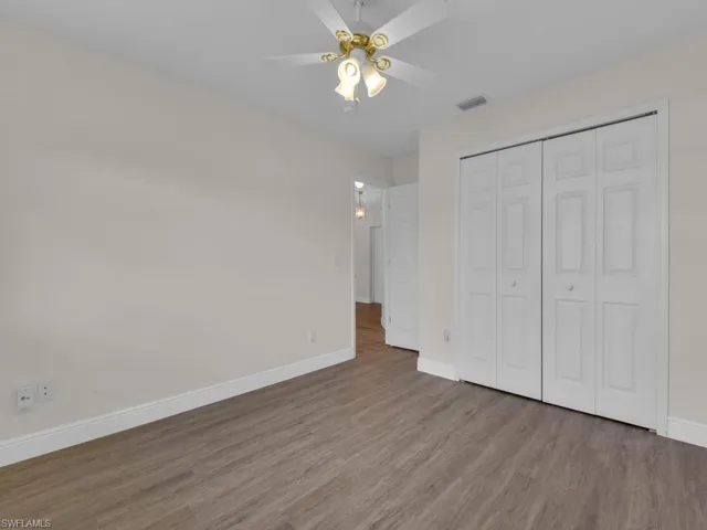 Interior room featuring wood-finish flooring, white walls, and white baseboards